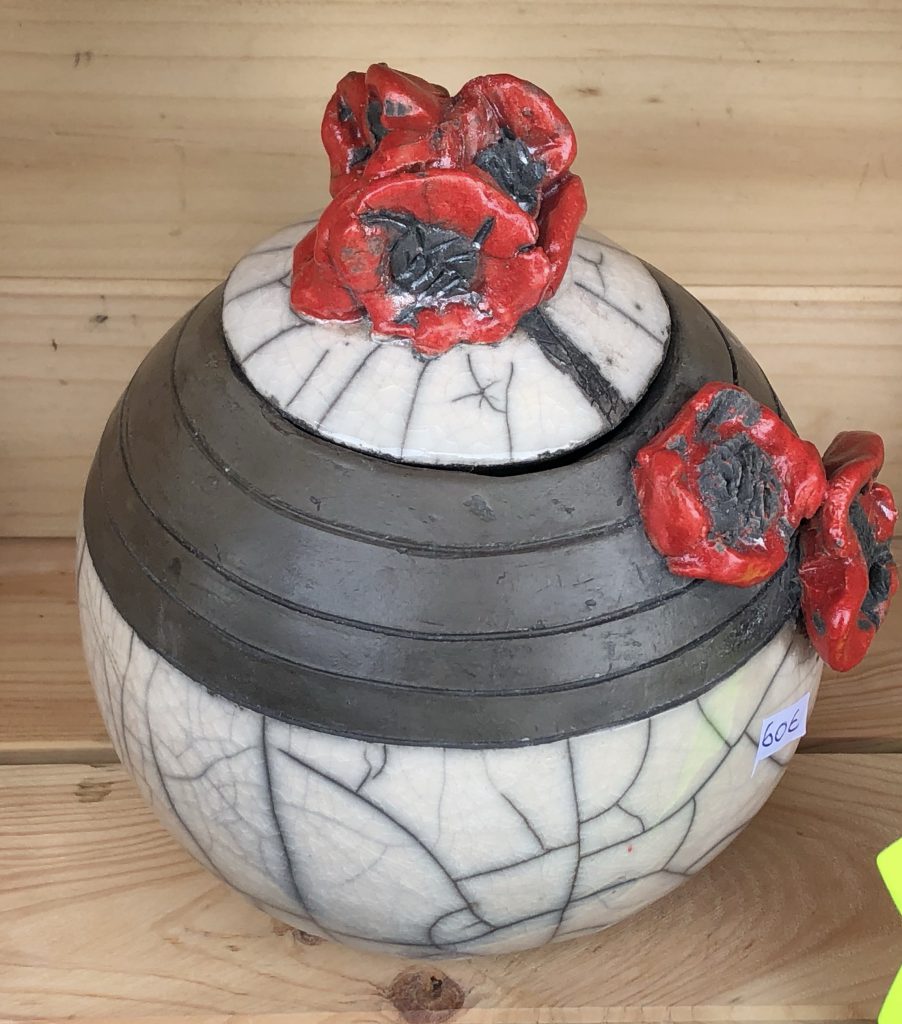 Vue d'une boîte en céramique cuite selon la technique du Raku. Coquelicots rouges en décoration